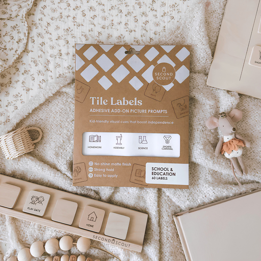 Pack of brown adhesive tile labels with school-related icons and words, displayed on a cream patterned blanket next to wooden blocks and a soft toy mouse.